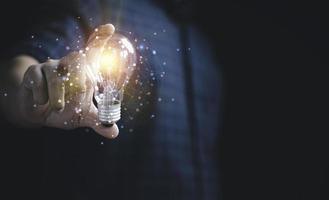 mano de hombre de negocios sosteniendo una bombilla con luz brillante para un pensamiento creativo e inteligente en busca de inspiración e innovación con el concepto de red. foto