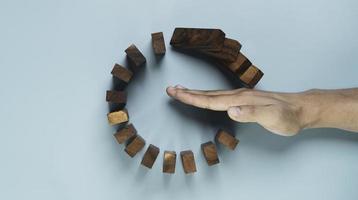 Top view and flat lay design of Businessman use gesture to stop wooden domino circle falling for insurance assurance and risk management concept. photo