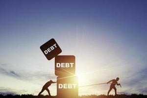 silueta de dos hombres empujando y tirando de cajas de peso de deuda apiladas para el concepto de deuda y libertad financiera. foto