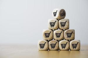 Wooden cube block stacking which print screen shopping trolley cart and investment graph for sale amount increasing and business growth concept. photo