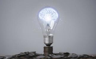 Glowing virtual brain inside lightbulb on coin stacking for creative thinking idea and innovation can make more money concept. photo