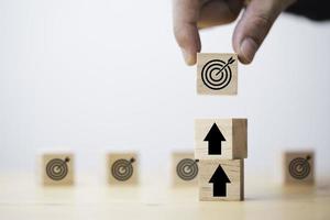 Businessman holding wooden cube block which print screen target board and lay down on up arrow block for enhance setup new challenges business objective concept. photo