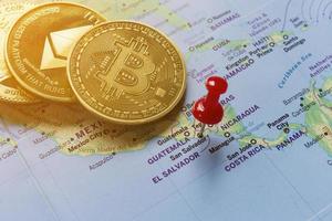 A red pin is pinned on the world map of El Salvador and there is a bitcoin next to it. photo