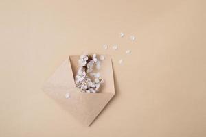 Kraft envelope with a spring twig and white spring flowers on a beige background photo