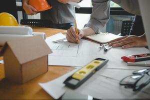 manos de arquitecto o ingeniero usando brújula de dibujo con plano en el escritorio en la oficina. equipo de arquitectos ingenieros discutiendo y verificando documentos y flujo de trabajo empresarial. concepto de construcción. foto