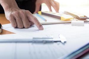 Hands of architect or engineer using drawing compass with blueprint on desk in office.Team of architects engineer discussing and check documents and business workflow.Construction concept. photo