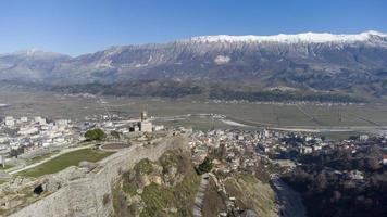 Aerial drone view of Gjirokaster cityscape on a winter sunny day. Gjirokaster castle view from above. City in a valley surrounded by mountains. Albania Unesco World Heritage Site. photo