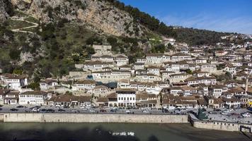 Aerial drone view of Berat, the city with a thousand windows. Unesco world heritage city. Cityscape and daily life happening on a sunny day. River flowing and mountains in the background. photo