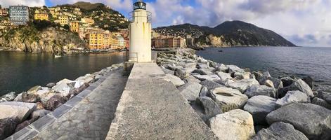 Wide angle view of the port of Camogli, from the breakwater, with the lighthouse in the foreground. In the background, the characteristic pastel-colored houses. photo