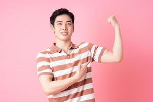 Young Asian man posing on pink background photo