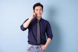 Portrait of young Asian businessman using smartphone on blue background photo