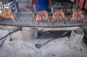 People are roasting chicken in the countryside on a simple grill, with blurred motion in the hands. photo