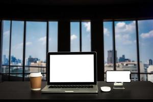 Front view workspace with computer, smartphone and tablet on white desk with blurred City background photo