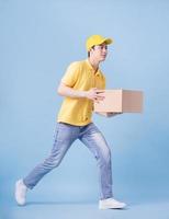 Full length image of Asian delivery man on blue background photo