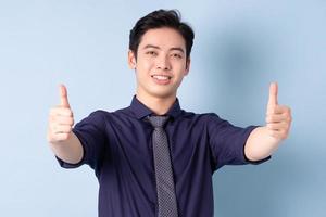 Portrait of young Asian businessman posing on blue background photo