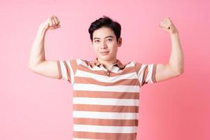 Young Asian man posing on pink background photo