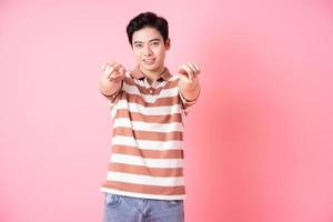 Young Asian man posing on pink background photo