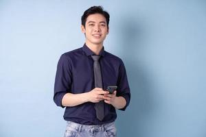 Portrait of young Asian businessman using smartphone on blue background photo