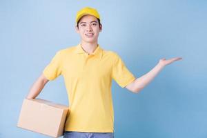 Image of young Asian delivery man on blue background photo