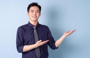 Portrait of young Asian businessman posing on blue background photo