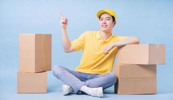 Image of young Asian delivery man on blue background photo