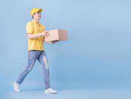 Full length image of Asian delivery man on blue background photo