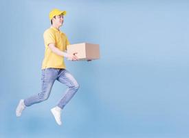 Full length image of Asian delivery man on blue background photo