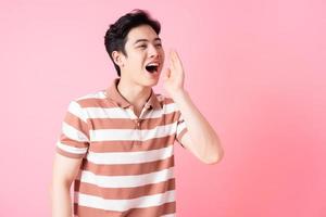 Young Asian man posing on pink background photo