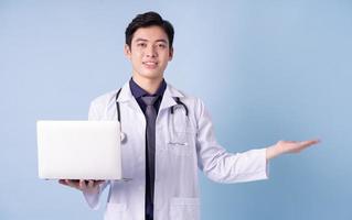 Portrait of young Asian male doctor on blue background photo