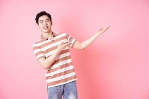 Young Asian man posing on pink background photo