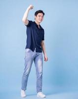 Full length image of young Asian man posing on blue background photo