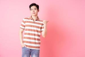 Young Asian man posing on pink background photo