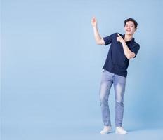 Full length image of young Asian man posing on blue background photo