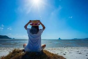 una mujer se siente feliz sentada en la playa vista tropical de tailandia. foto