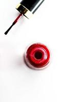 An opened bottle of red nail polish on white background table top view photo