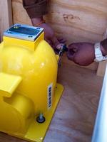 The worker spins the padlock code to unlock the mechanical shutter of the radioactive instrument holder photo