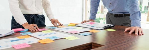 grupo creativo de empresarios que hacen una lluvia de ideas utilizan notas adhesivas para compartir ideas sobre la decisión de la mesa eligiendo el concepto para desarrollar un plan en la sala de conferencias de negocios.