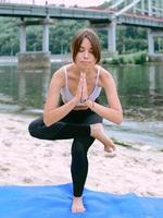 young fit woman in sportswear in different yoga asanas outdoor on the beach by the river. Yoga and sport concept photo
