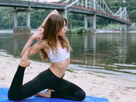 young fit woman in sportswear in different yoga asanas outdoor on the beach by the river. Yoga and sport concept