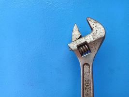 Rusty Adjustable Wrench isolated on blue background, copy space concept for industrial work and mechanical tools photo