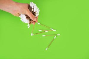 cotton sticks for cleaning the ears in the hand of a young girl on a green background. Close-up. top view. zero waste photo