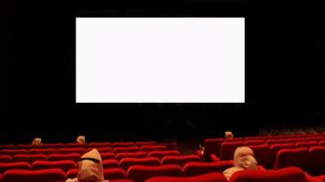 People in the cinema auditorium with empty white screen. photo