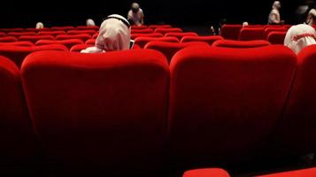 People in the cinema auditorium with empty white screen. photo