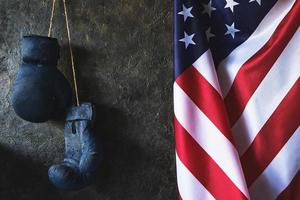 Viejos guantes de boxeo cuelgan en la pared junto a la bandera de los Estados Unidos de América.