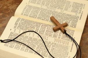 Wooden christian cross with rope on open holy bible. photo