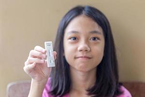 Little child girl holding a negative test device. Asian kid girl showing her negative Coronavirus - Covid-19 rapid test