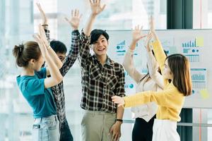 Happy successful asian business team giving a high fives gesture as they laugh and cheer their success. photo