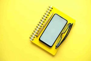 top view of smart phone and notepad on yellow background photo