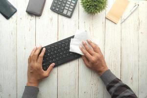 disinfecting keyboard with a white tissue on table photo