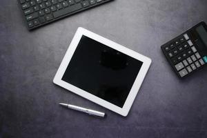 top view of digital tablet with office suppliers on black background photo